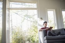 Человек сидит на диване, с цифровым планшетом — стоковое фото