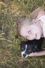 Chica abrazando un negro y blanco perro - foto de stock