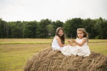 Girls sitting on haystack playing. — Stock Photo