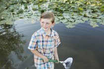 Jeune garçon debout en eau peu profonde — Photo de stock