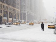 Человек, идущий по городу в снегу — стоковое фото