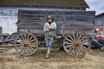 Cowboy leaning against wooden wagon — Stock Photo