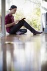Mann sitzt auf dem Boden, mit digitalem Tablet — Stockfoto