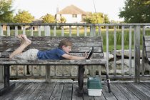 Garçon sur banc à l'aide d'une tablette numérique . — Photo de stock