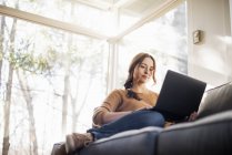 Woman on sofa looking at laptop — Stock Photo
