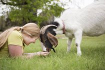 Mädchen liegt mit Ziege im Gras — Stockfoto
