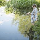 Молодий хлопчик рибалить у спокійній воді — стокове фото