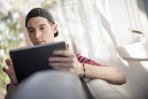 Homem sentado no sofá, com tablet digital — Fotografia de Stock
