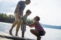 Padres e hijo pasando tiempo junto a un lago - foto de stock