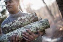 Homme transportant du bois de chauffage dans la forêt — Photo de stock