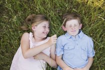 Brother and sister lying on the grass — Stock Photo