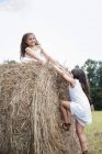 Meninas jogando por um grande haybale — Fotografia de Stock