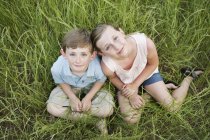 Brother and sister sitting side by side — Stock Photo