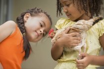 Girls holding a chicken — Stock Photo
