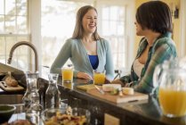 Women seated at a kitchen counter — Stock Photo