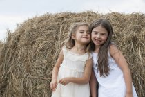 Girls standing by a large haybale — Stock Photo