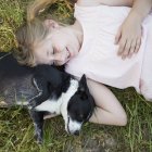Menina abraçando um cão preto e branco — Fotografia de Stock