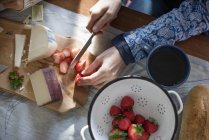 Femme tranchant des fraises sur une table — Photo de stock