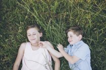 Hermano y hermana tendidos en la hierba - foto de stock