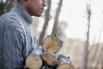 Uomo che porta legna da ardere nella foresta — Foto stock