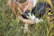 Девушка обнимает черно-белую собаку — стоковое фото