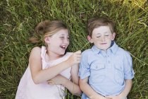 Брат и сестра лежат на траве — стоковое фото