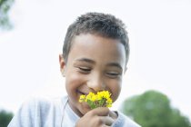 Junge lächelt und hält Blume. — Stockfoto