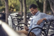 Homem em um parque olhando para um telefone inteligente — Fotografia de Stock