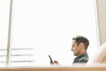 Hombre sentado sosteniendo un teléfono inteligente - foto de stock