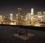 Casal sentado em um tapete em um telhado — Fotografia de Stock