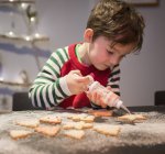 Chico decorando galletas de Navidad - foto de stock