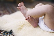 Bebé acostado en una alfombra de piel de oveja - foto de stock