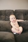 Baby sitting propped up on a sofa — Stock Photo
