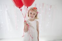 Giovane ragazza che tiene palloncini rossi — Foto stock
