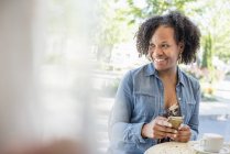 Женщина держит смартфон в кофейне — стоковое фото