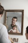 Pais com seu bebê, olhando no espelho . — Fotografia de Stock