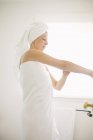 Mujer en toalla blanca en un baño - foto de stock