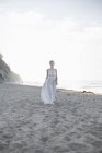 Mulher de pé em uma praia de areia . — Fotografia de Stock