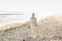 Mulher andando ao longo de uma praia arenosa — Fotografia de Stock