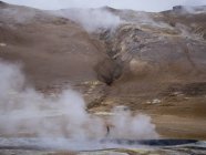 Person at steamy edge of a hot spring. — Stock Photo