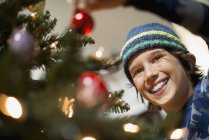 Boy placing baubles on Christmas tree — Stock Photo