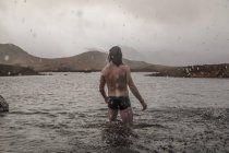Hombre de pie muslo profundo en el mar - foto de stock
