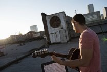 Homem tocando uma guitarra em um telhado — Fotografia de Stock