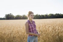 Frau steht in einem Weizenfeld — Stockfoto