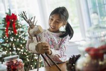 Girl assembling twig figure of reindeer — Stock Photo
