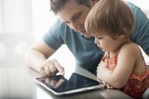 Батько і дочка дивляться на цифровий планшет — стокове фото