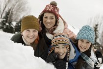 Children grouped laughing by a snow bank. — Stock Photo