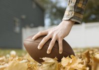 Mão segurando um futebol oval — Fotografia de Stock