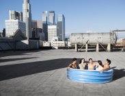 Friends in inflatable pool on rooftop — Stock Photo