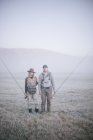 People in mist carrying fishing rods. — Stock Photo